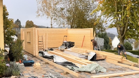 Die ersten Holzwände stehen; weitere Bauteile warten auf ihre Montage.