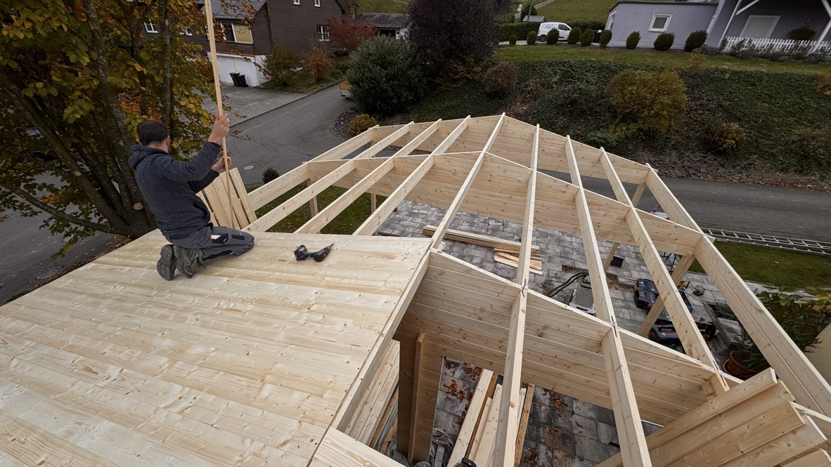 Dachbalken und die schrittweise verlegte Holzbeplankung.